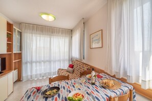 A dining area with a table set for two, featuring a fish pattern tablecloth, a basket of bread, and plates of food. - Vacation house with panoramic terrace (Bibione)