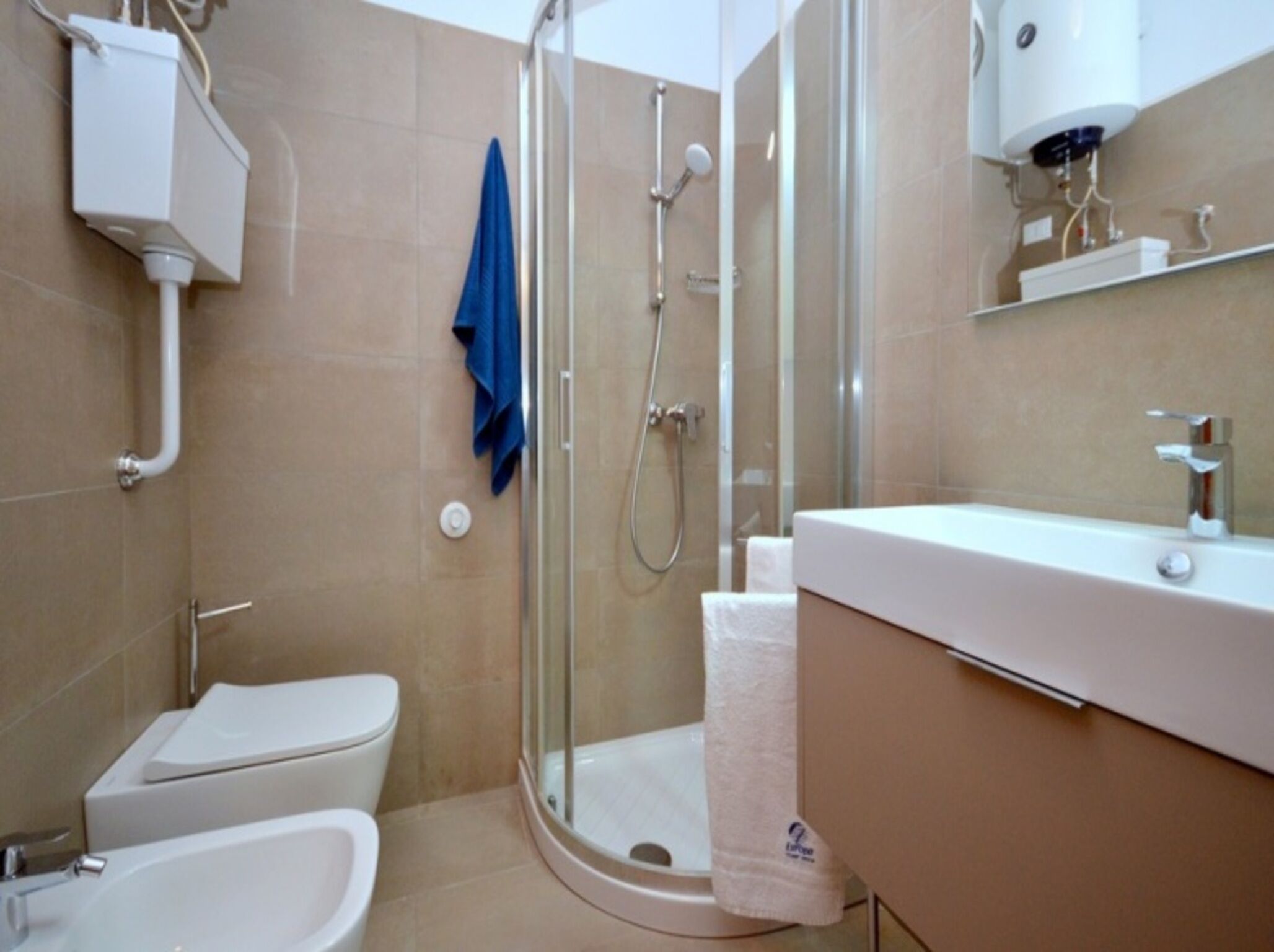 Un bagno moderno con doccia vetrata, un water bianco e un lavabo con specchio sopra.