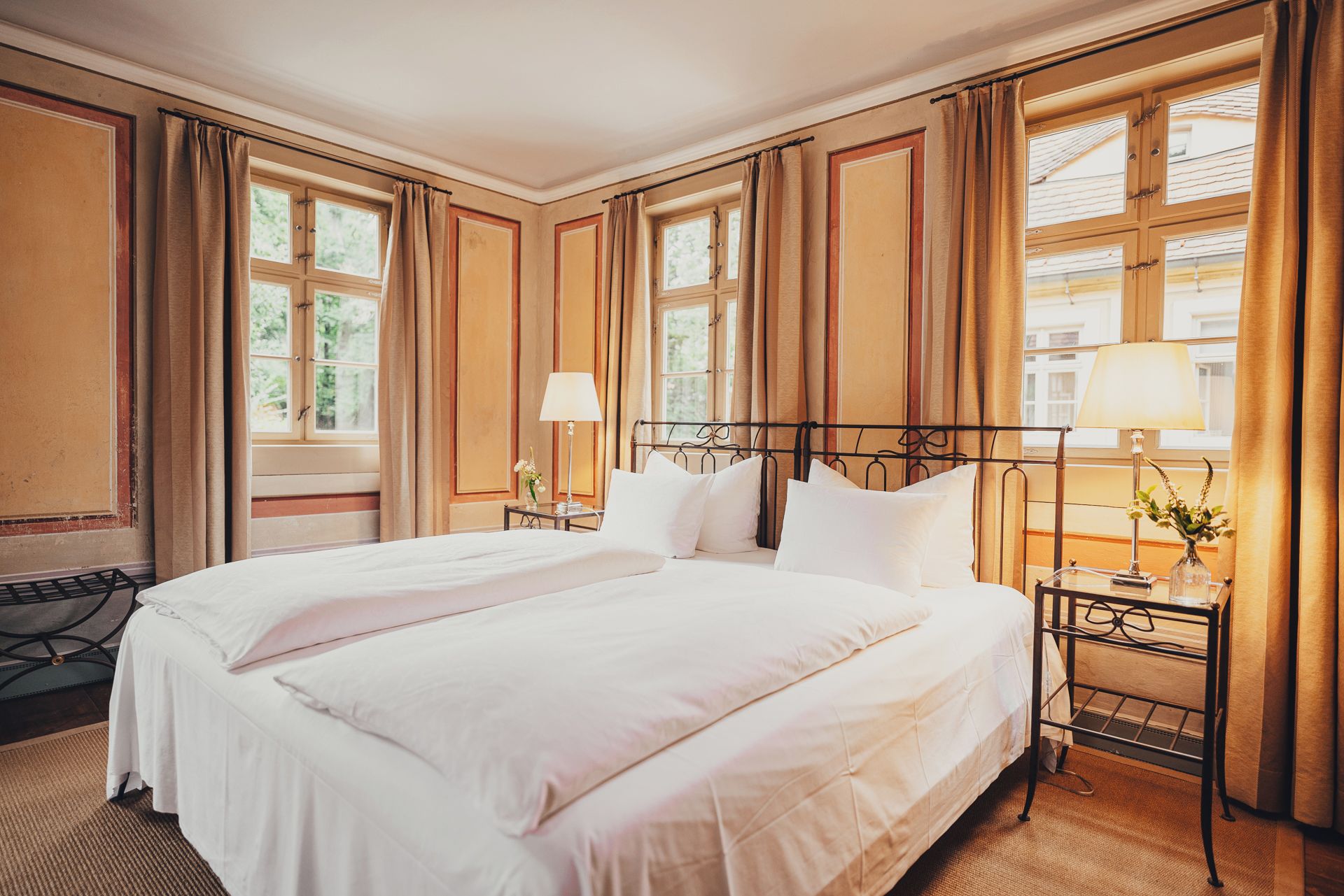A hotel room with a large bed, two bedside tables, and a window with curtains.