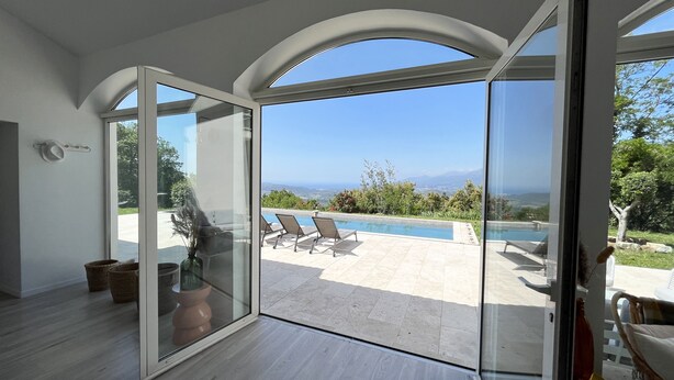 Un interior moderno con un vidrio que da a una zona de piscina exterior con vista al océano.