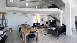 Un apartamento moderno con comedor, sala de estar y una escalera que sube a un nivel superior.