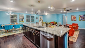 A modern kitchen with a central island, dark wood flooring, and blue walls. - Luxury Island Home – Pool Oasis, Near Downtown! (Savannah)
