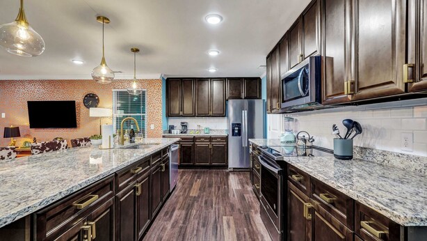 A modern kitchen with dark wood cabinets, granite countertops, and stainless steel appliances. - Luxury Island Home – Pool Oasis, Near Downtown! (Savannah)