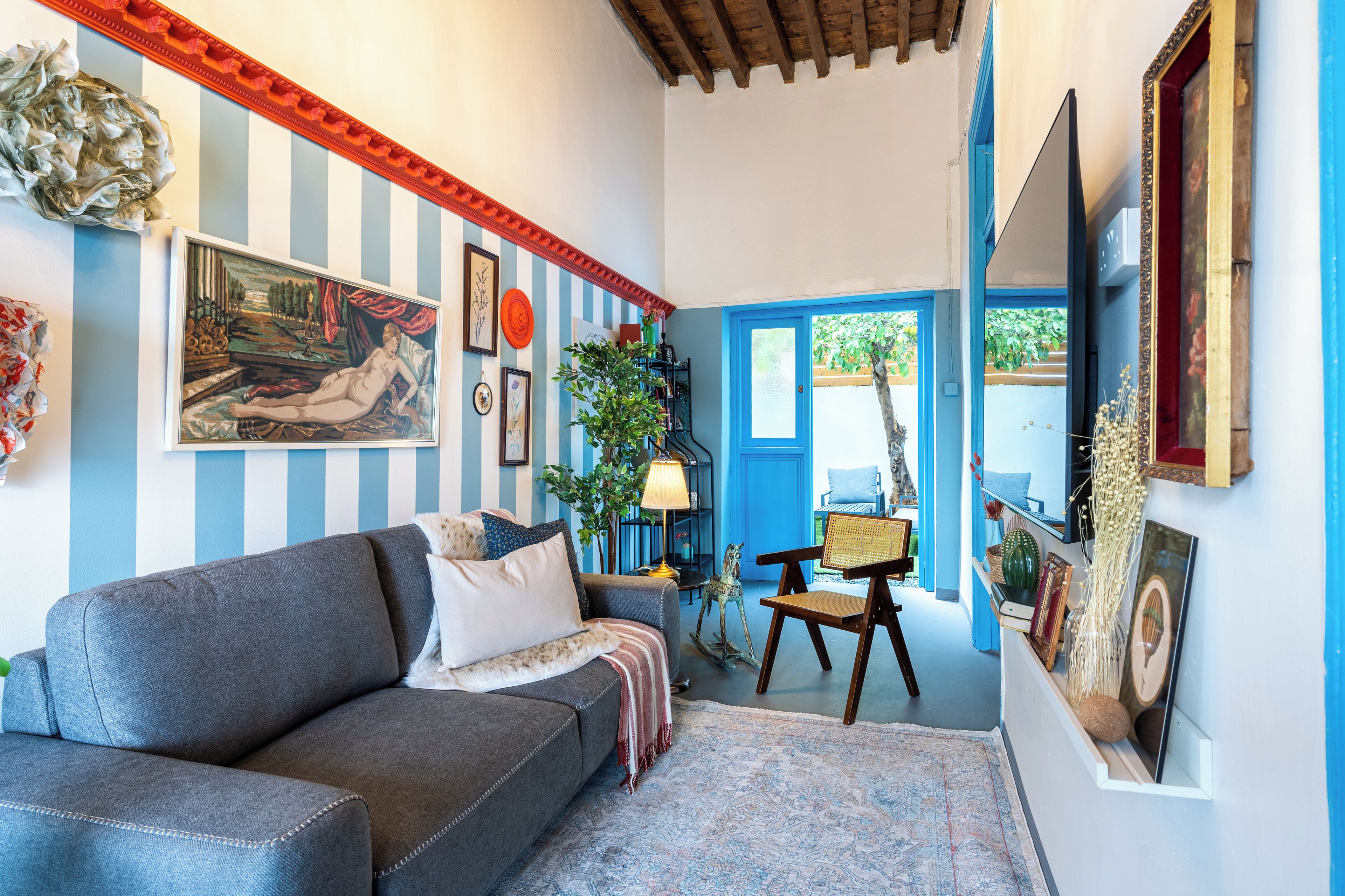 A living room with a sofa, a lamp, and a door leading outside.