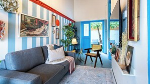 A living room with a sofa, a lamp, and a door leading outside.