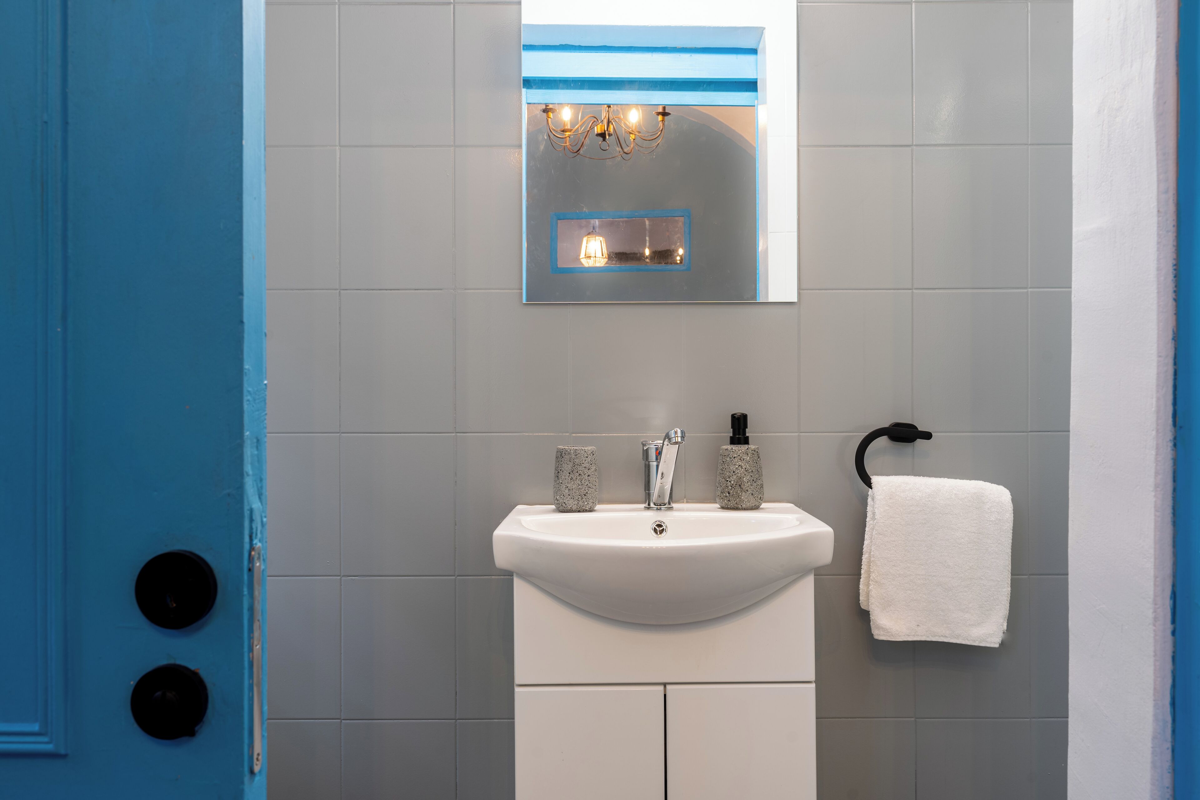 A bathroom with a white sink, a mirror, and a towel rack.