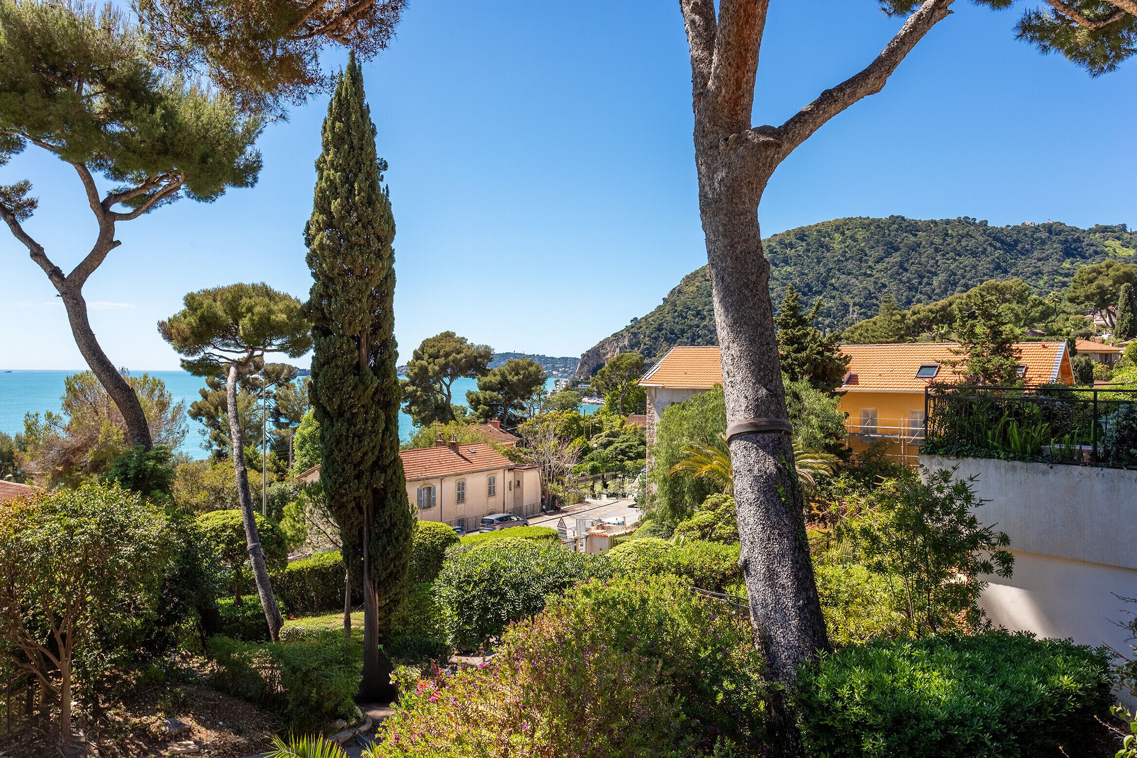 A coastal town with Mediterranean architecture, lush greenery, and a clear view of the sea.