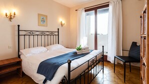 A bedroom with a bed, a bench, a chair, and a window with curtains. - LA SOLEILLADE VI4451 By Riviera Holiday Homes (Eze)