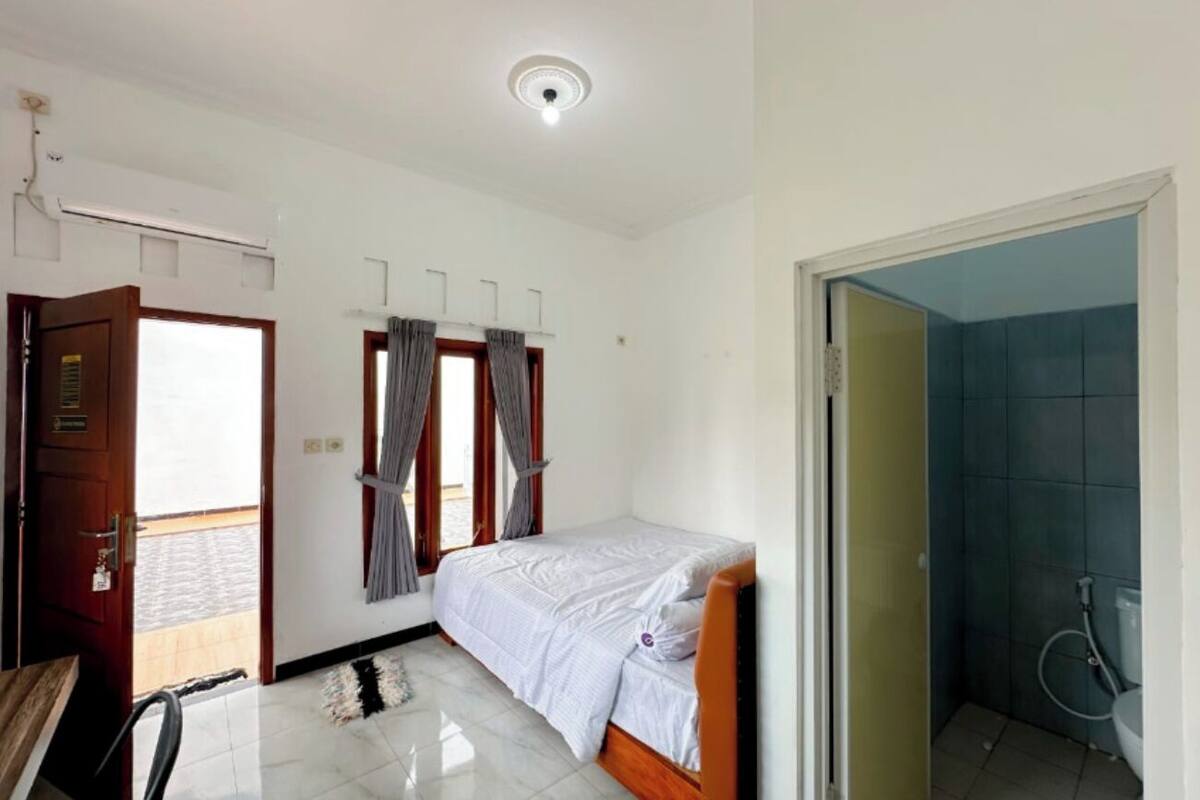 Une petite chambre propre, avec un lit, un bureau et une salle de bain.