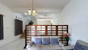 Un salon comprenant un ensemble de canapés, une cloison en bois et un escalier menant à l’étage supérieur.