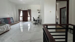 Un vaste espace de vie comprenant un canapé, une table à manger avec des chaises et un escalier.