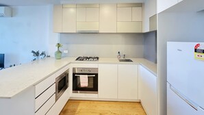A modern kitchen with white cabinetry, a built-in oven, a gas stove, and a stainless steel refrigerator.