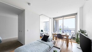 A modern bedroom with a bed, a desk, and a large window.