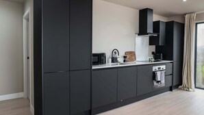 Een moderne keuken met donkere kastjes, een ingebouwde magnetron, een koffiezetapparaat en een fornuis.