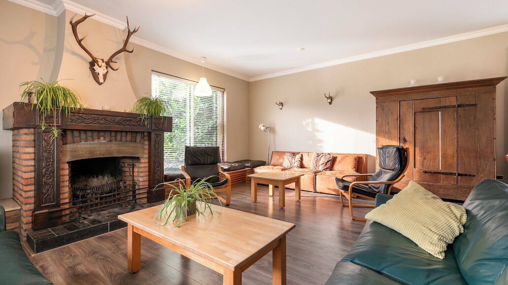 Ein Wohnzimmer mit Kamin, Ledermöbeln und dekorativen Geweihen an der Wand.