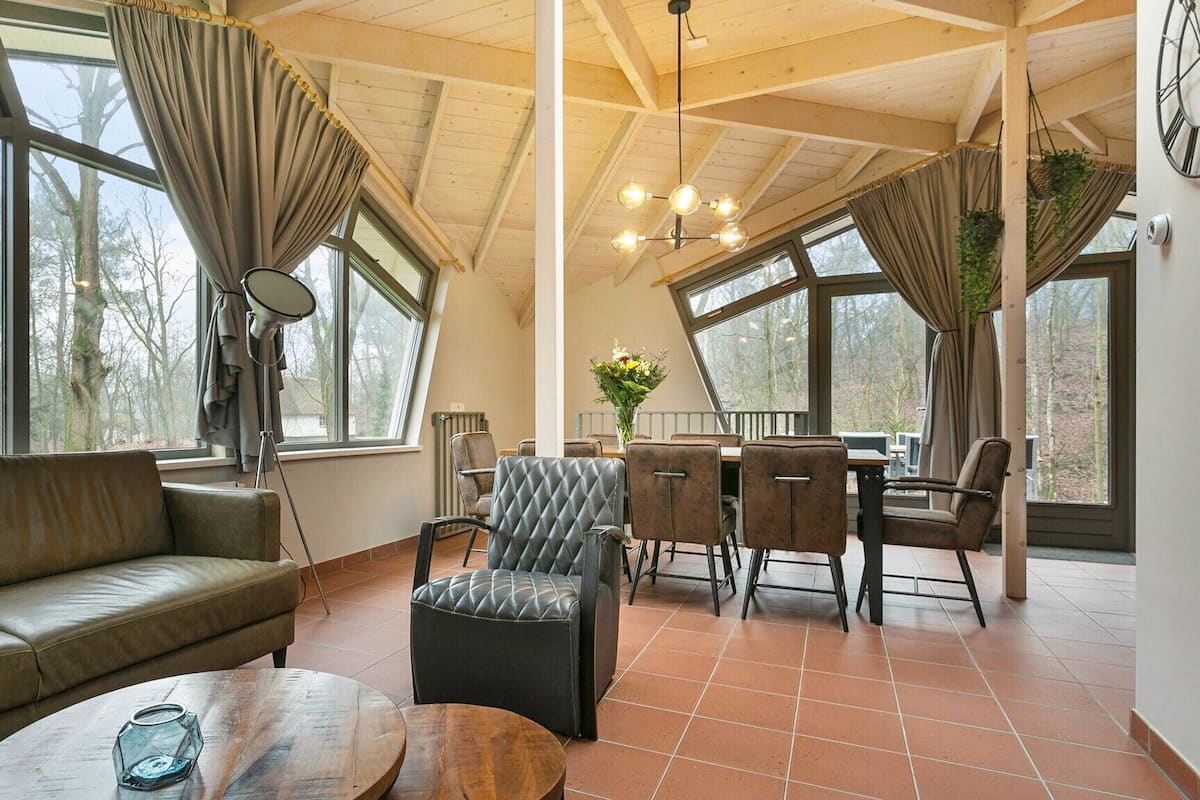 Una habitación amplia con un gran ventanal, un sofá, una mesa de comedor con sillas y una mesa de centro.