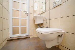 A bathroom with a toilet, a sink, and a mirror. - Riverside GuestHouse (Kozhikode)