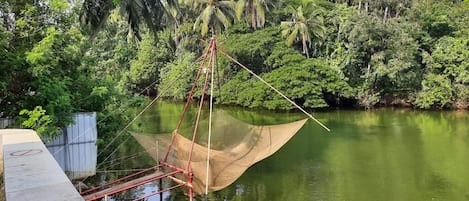 Un cadre paisible au bord de la rivière, agrémenté d’une structure traditionnelle de pêche au filet.