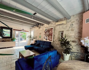 A spacious lobby with a blue sofa, a wooden coffee table, and a stone wall. - CHARMING FARMHOUSE WITH WOODED GROUNDS AND SWIMMING POOL (Avignon)