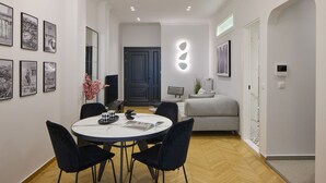 A modern living room with a dining area, featuring a round table, black chairs, a grey sofa, and a black door. - The Athenian Chic & Elegant Apartments in Kolonaki (Athens)