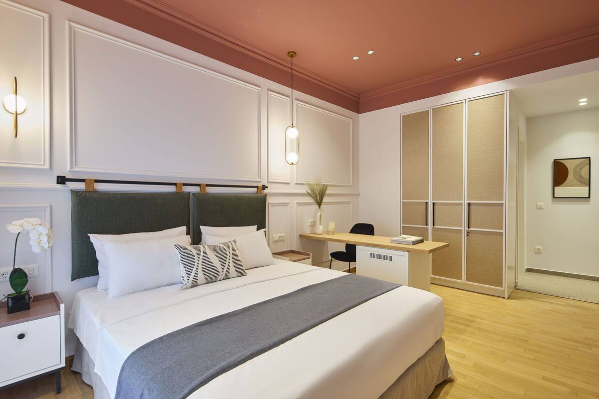 A neatly arranged hotel room with a large bed, bedside table, and a desk area.