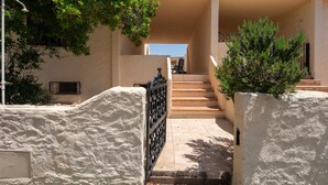 A staircase leading to a building with a beige exterior, a metal gate, and a small tree. - Sabbia Marina (Budoni)