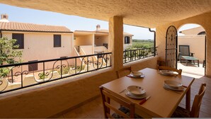 A balcony with a table set for dining, overlooking a residential area with terracotta roofs. - Sabbia Marina (Budoni)