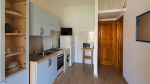 A compact kitchen with a sink, stove, microwave, and a small table. - Resinosa in Agrustos (Budoni)