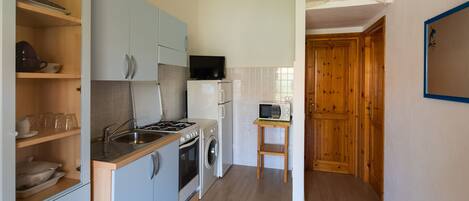 A compact kitchen with a sink, stove, microwave, and a small table.