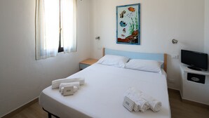 A hotel room with a bed, a TV, a painting of fish, and a window with curtains. - Resinosa in Agrustos (Budoni)