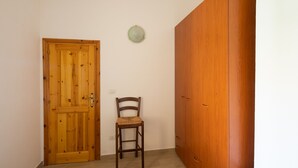 Une porte en bois, une chaise et une armoire dans une pièce aux murs blancs.