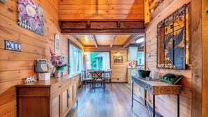 A wooden cabin interior with a kitchen, dining area, and a view of the outdoors. - Splash at the Creek, roast marshmallows & play ping-pong together – Wade 'N Bear (Sevierville)