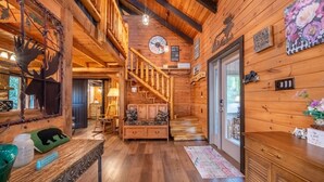 A wooden cabin interior with a staircase, a clock, a sofa, and a reception desk. - Splash at the Creek, roast marshmallows & play ping-pong together – Wade 'N Bear (Sevierville)