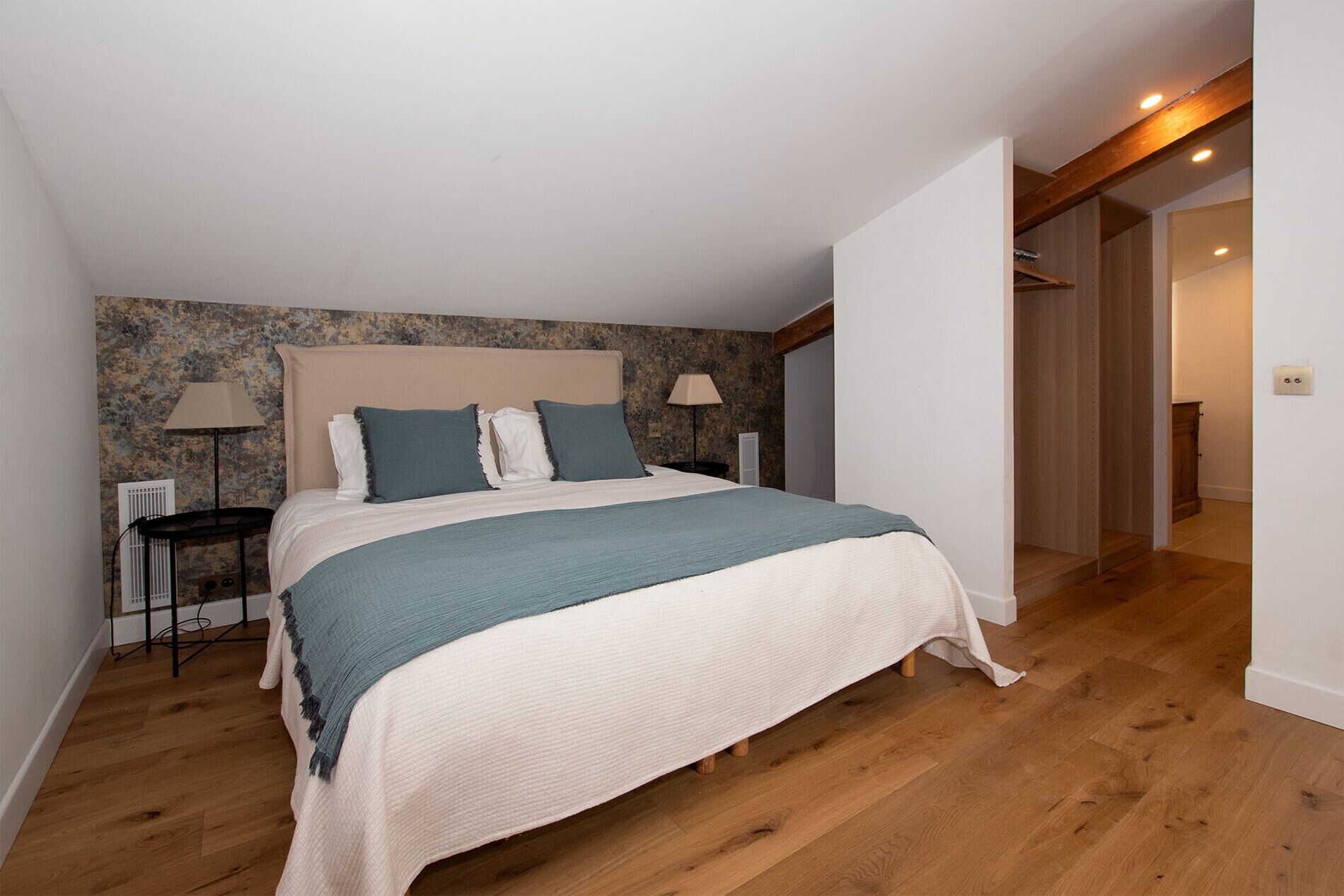 Ein Schlafzimmer mit einem großen Bett, zwei Nachttischen, einer Lampe und Holzboden.