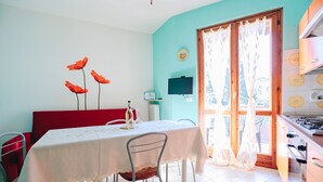 Un comedor con una mesa, sillas, un sofá rojo y una zona de cocina con estufa.