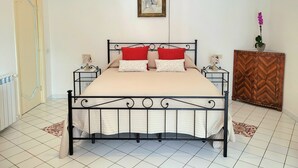 A neatly arranged bedroom with a bed, bedside tables, a wooden cabinet, and a framed picture on the wall. - Elle, a stone's throw from the Sea (Positano)