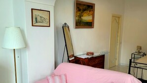 A room with a pink sofa, a standing lamp, a dresser, a mirror, and two framed pictures on the wall. - Elle, a stone's throw from the Sea (Positano)