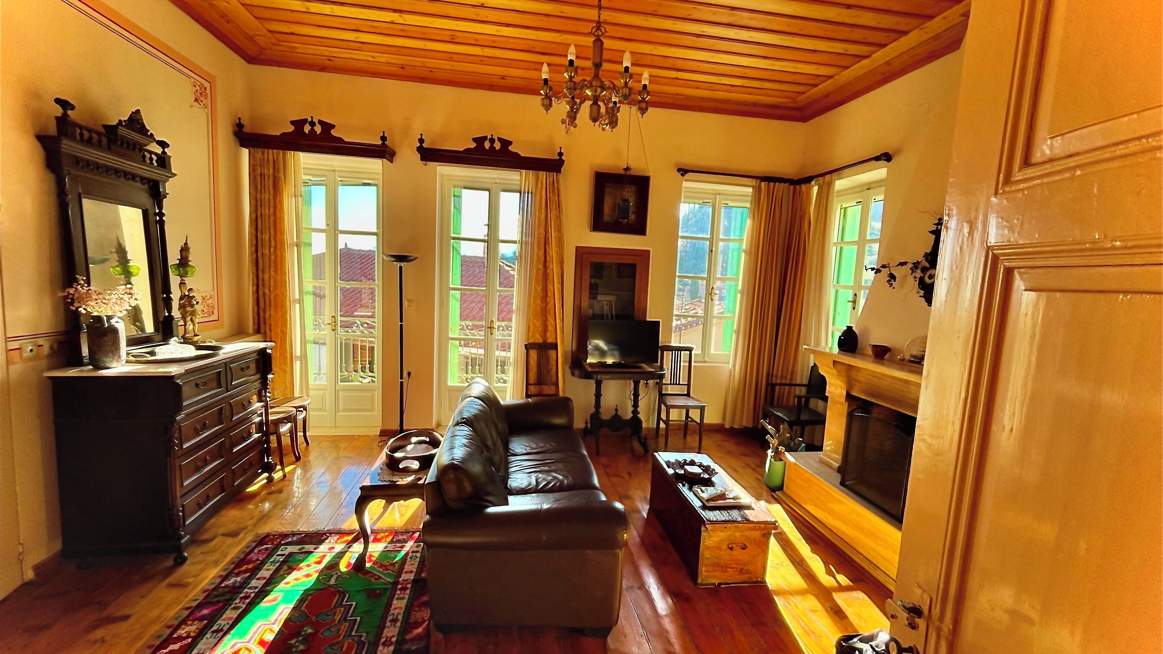 Uma sala de estar acolhedora com lareira, um sofá, uma televisão e uma janela grande com cortinas.