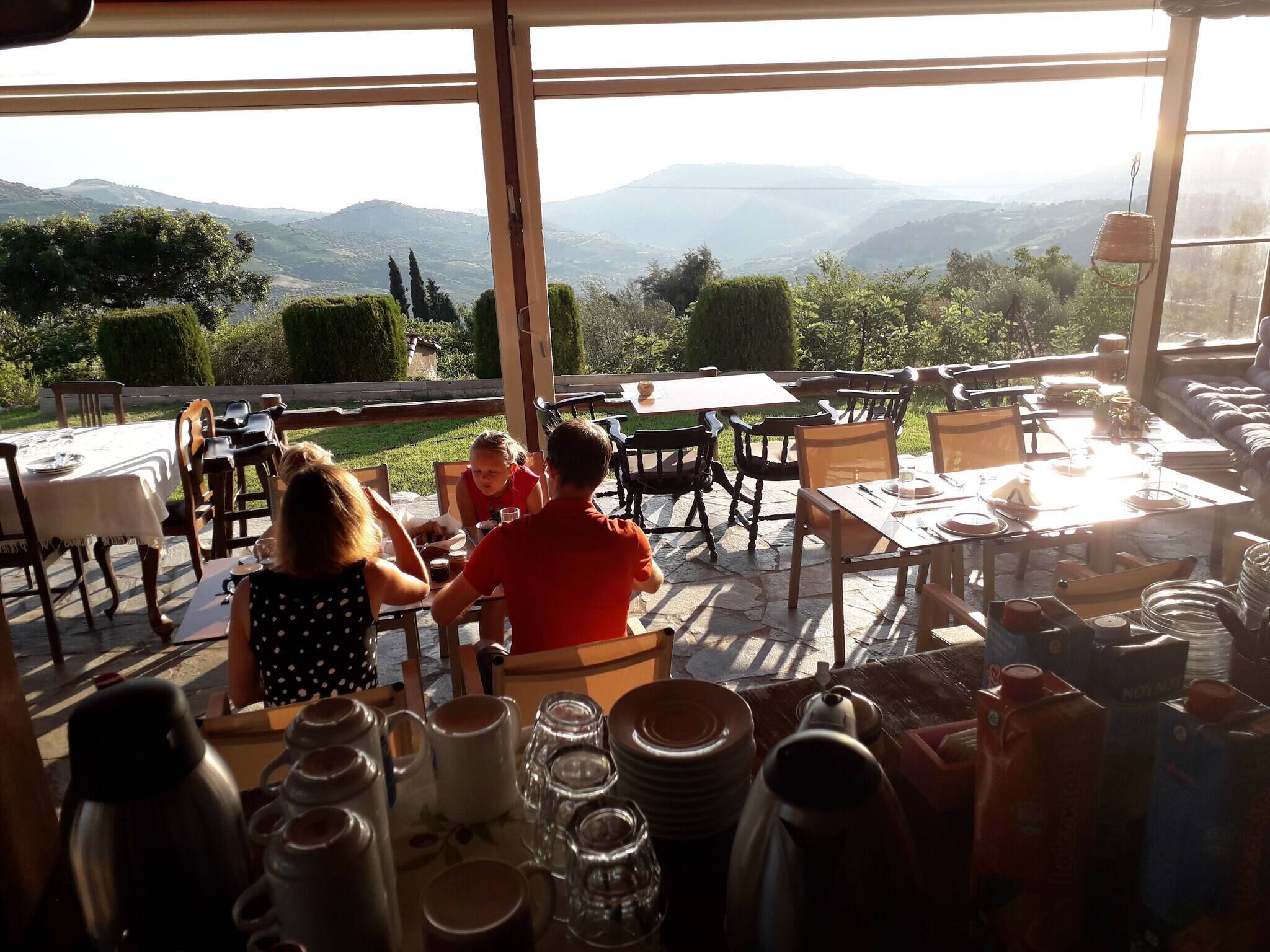 An outdoor dining area with tables and chairs, a view of the mountains, and a large window.