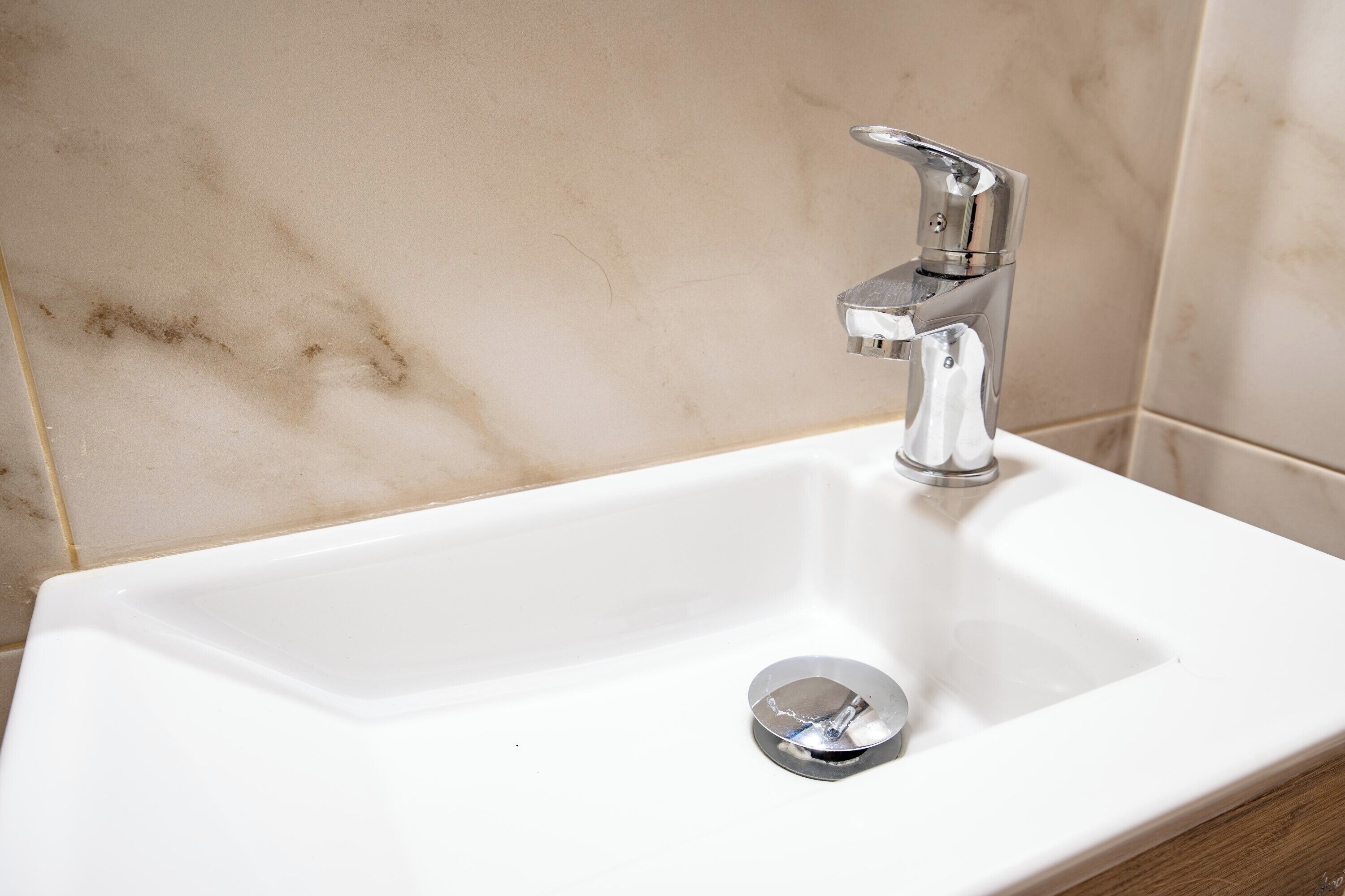 A white bathroom sink with a chrome faucet and a single chrome drain cover.