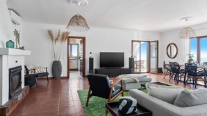 A spacious living room with a fireplace, a large TV, and a dining area with chairs. - Retreat with sea views & private heated pool! (Almuñecar)