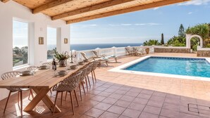 A wooden dining table with chairs, a pool, and a view of the sea. - Retreat with sea views & private heated pool! (Almuñecar)