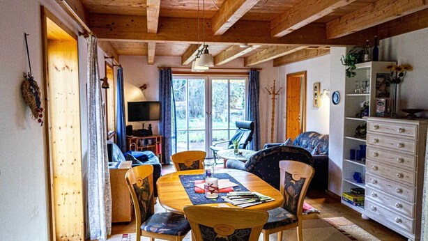 Ein gemütliches Blockhaus-Interieur mit Essbereich, einer Couch und einem Bücherregal.