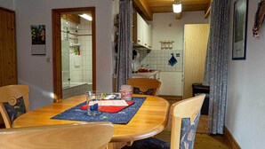 Ein Essbereich mit einem Holztisch, vier Stühlen und einer Küche im Hintergrund.