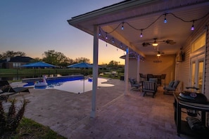 A covered patio with a pool, outdoor furniture, and string lights. - Peacock Shores | Team Joseph Ellen (Jacksonville)