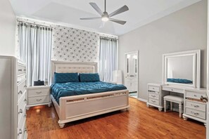Ein Schlafzimmer mit Bett, Schminktisch, Kommode und Deckenventilator.