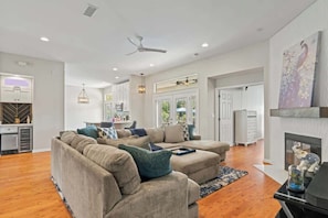 A spacious living room with a sectional sofa, a fireplace, and a kitchen in the background. - Peacock Shores | Team Joseph Ellen (Jacksonville)