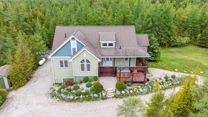 A two-story house with a covered porch, a front deck, and a driveway leading to the entrance.