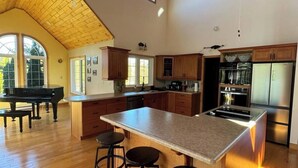 A spacious kitchen with wooden cabinets, a large island with stools, and a built-in oven.