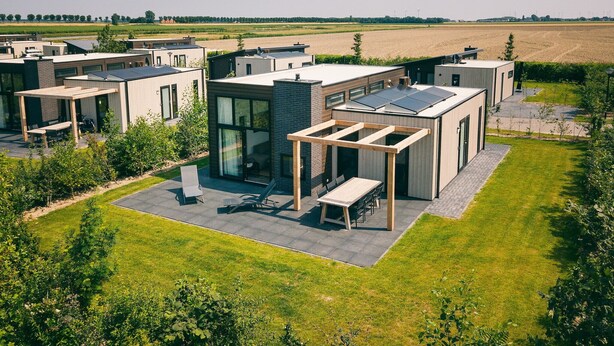 A modern residential complex with multiple houses, a central communal area with a pergola, and a well-maintained lawn. - Ground floor bungalow for 4 persons (Herkingen)